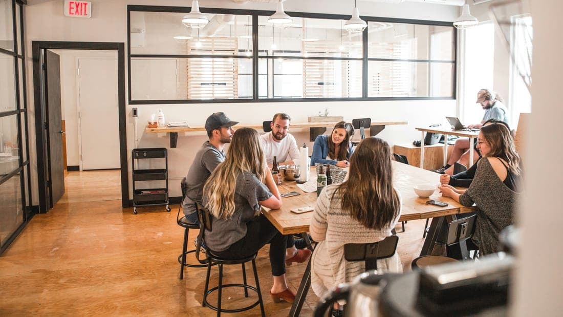 A team talking around a long wooden table in a bright office