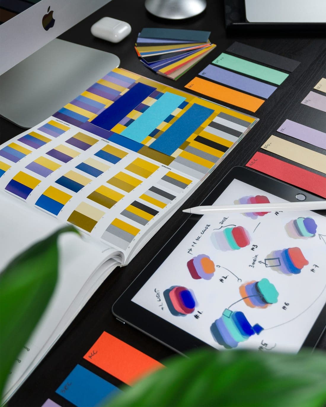Colour swatches and a tablet with sketches on a dark desk