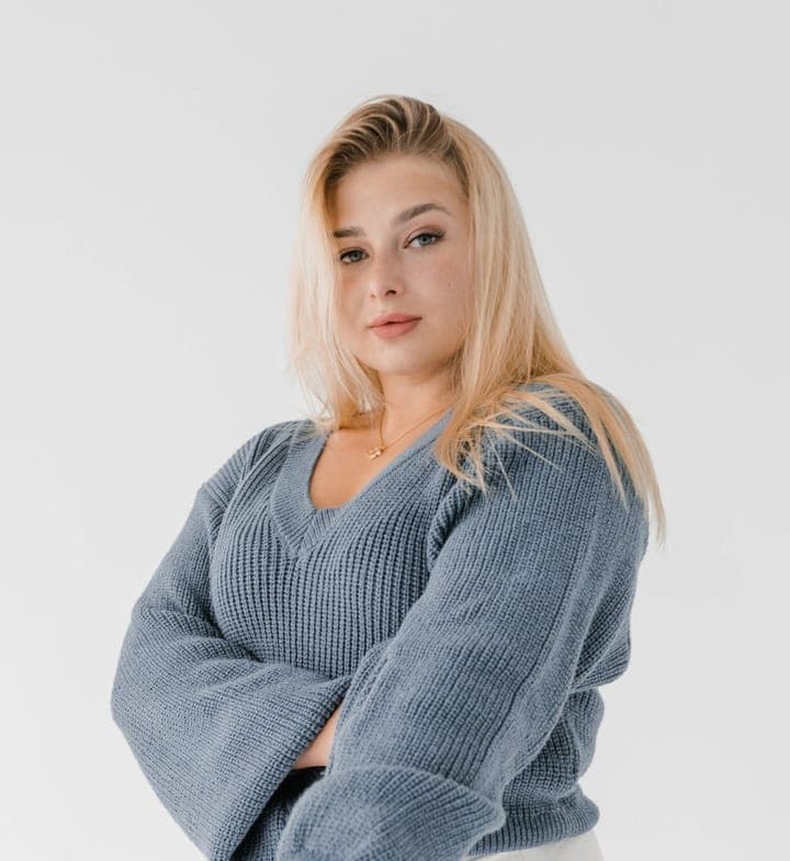 A woman with long blonde hair in a grey knit sweater