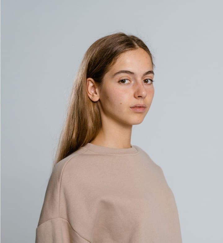 A young woman with long hair in a beige sweatshirt