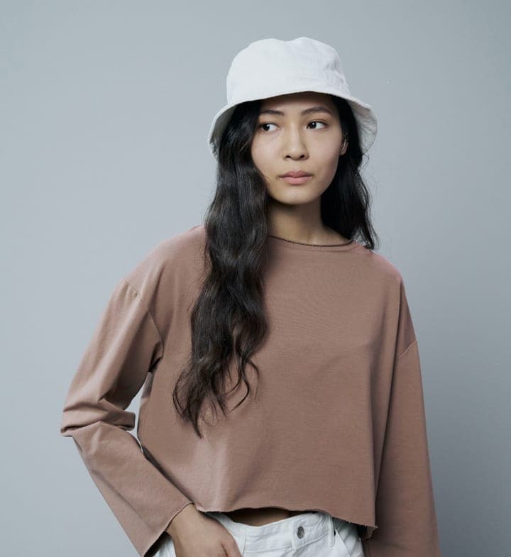 A woman with long dark hair in a white bucket hat