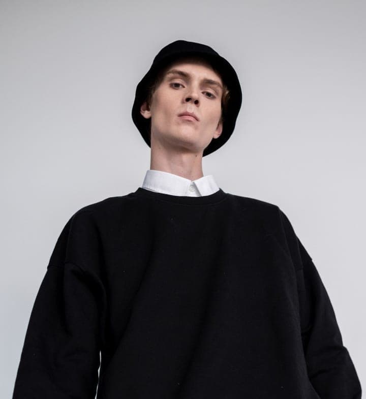 A young man in a black bucket hat and black sweater