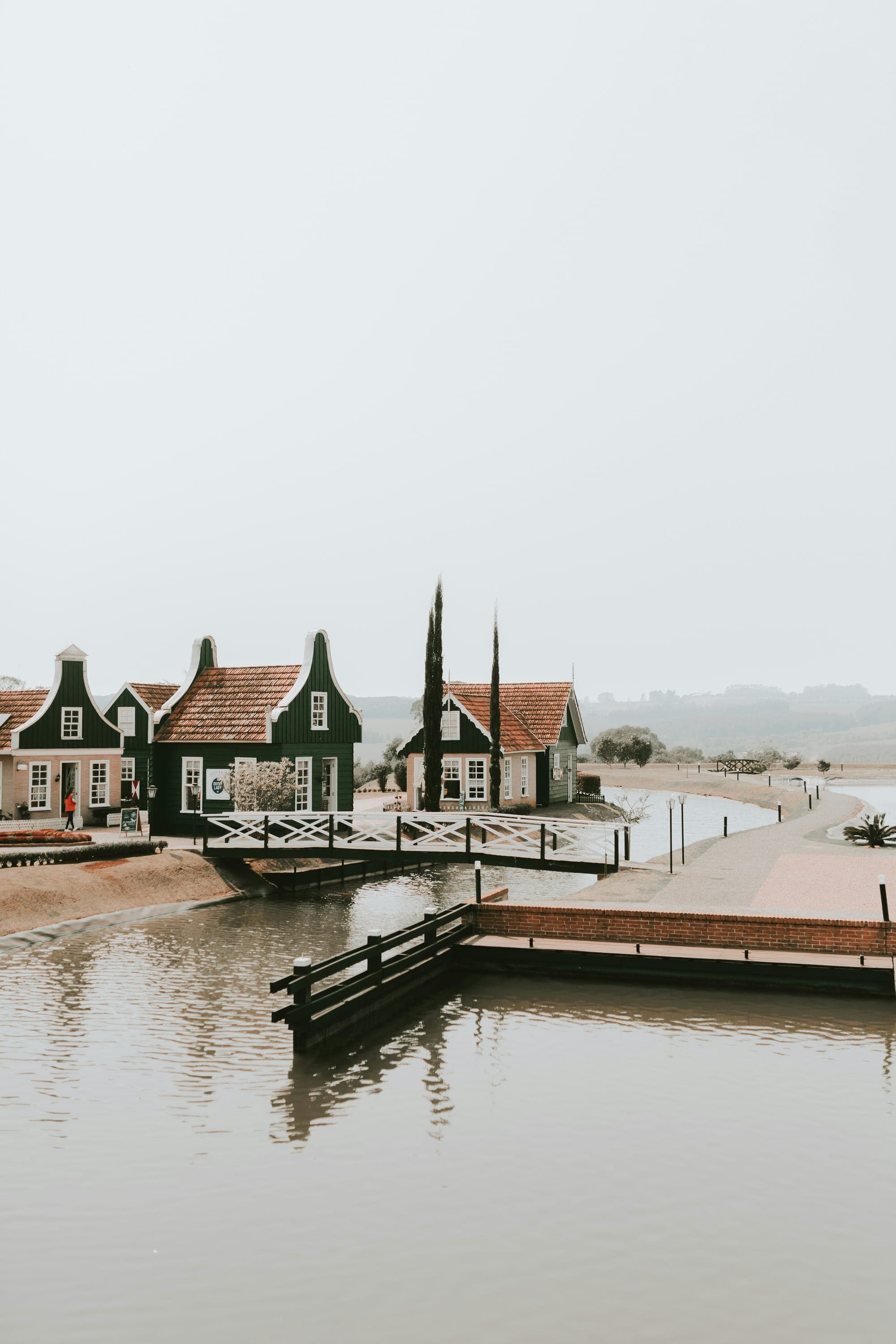Green wooden houses and a jetty beside calm water