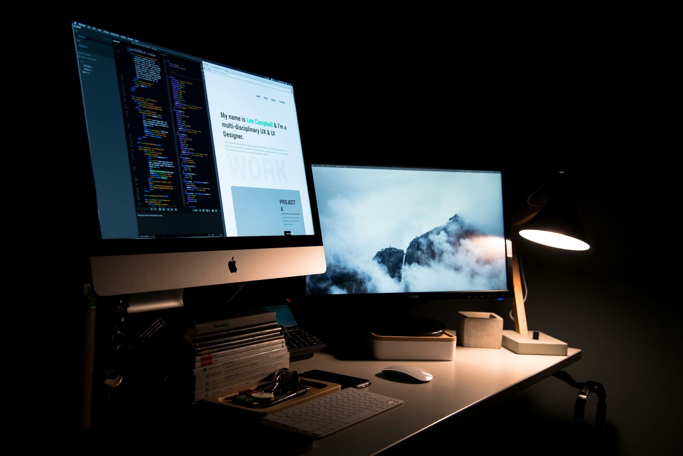 A dark desk with two monitors showing code and a website