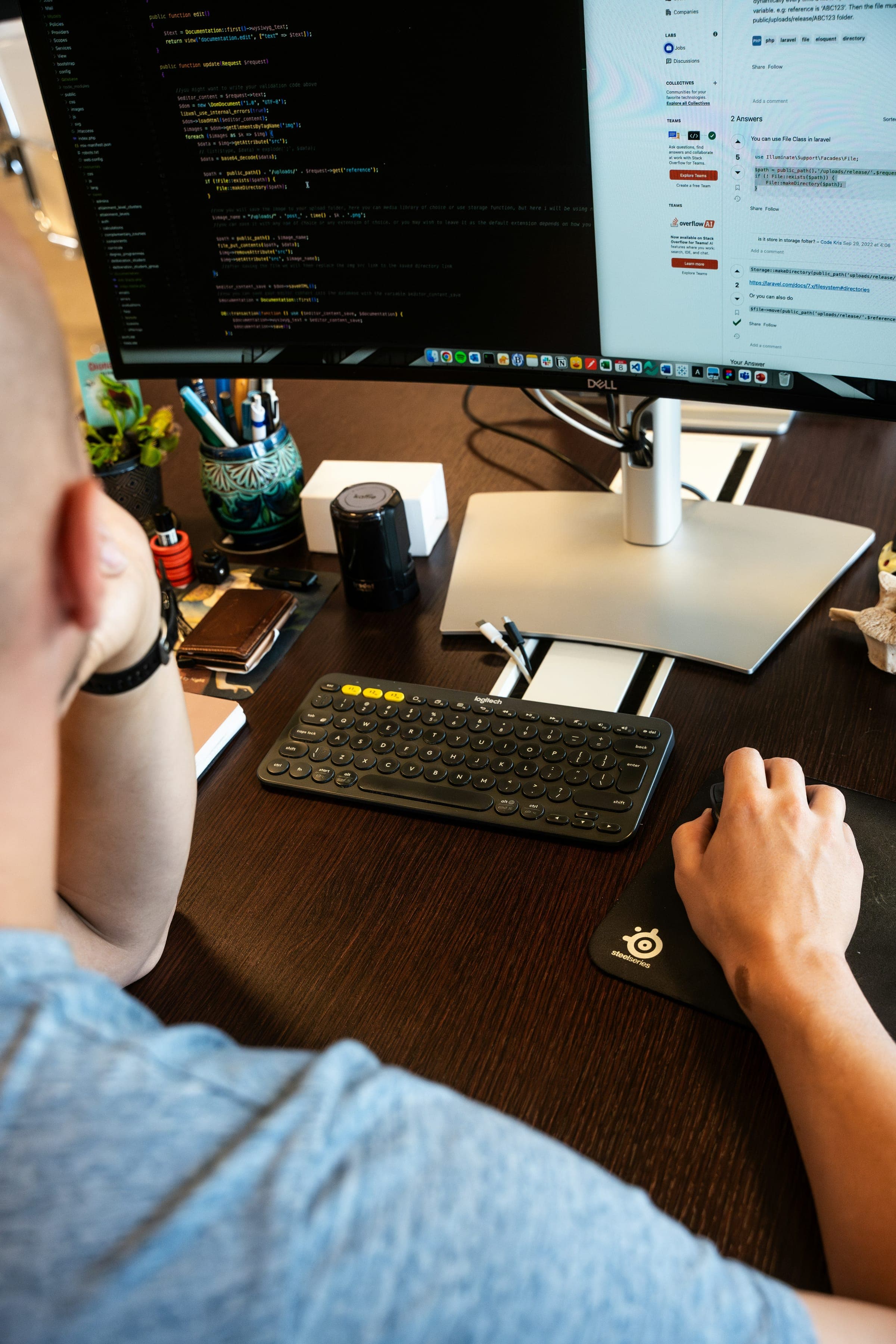 A developer typing at a desk with code on a large monitor